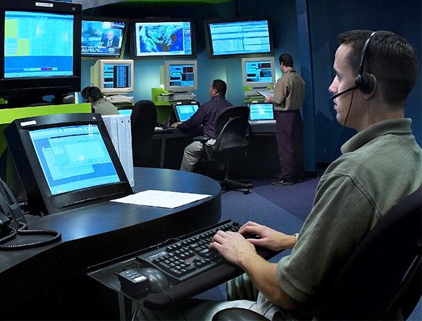 三名hg皇冠官网网络运营员工在电脑和电视显示器上监控数据