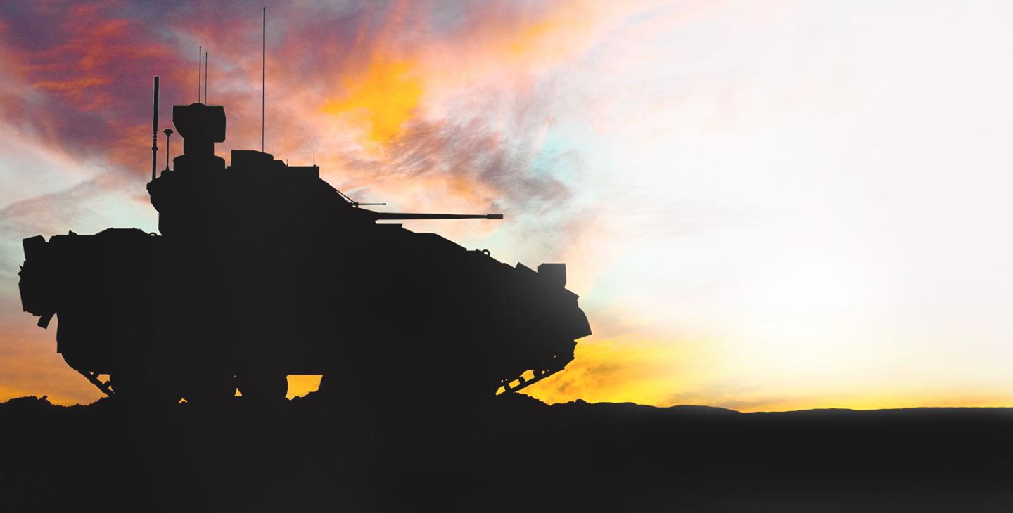 一辆军用坦克在夕阳下行驶的剪影